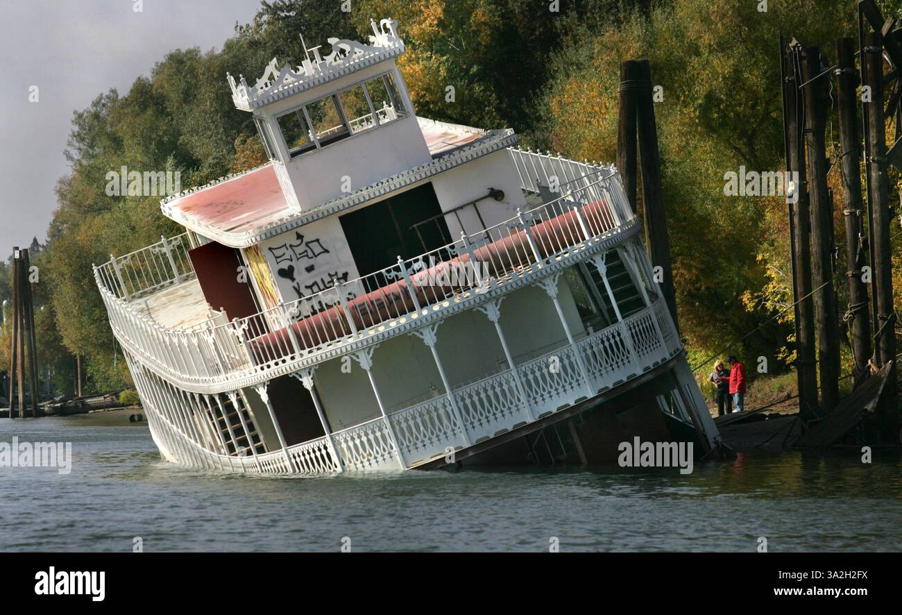 LEDE, Un agent de l'application du Code de West Sacamento et un employé de sauvetage de bateaux discutent d'un bateau à pédales autrefois utilisé dans un film de John Wayne qui a failli couler cette semaine au large d'une marina de West Sacramento. S'il était tombé, le bateau aurait découvert de la bonne compagnie sur le fond de la rivière Sacramento. Un nombre incalculable de navires ont coulé au fil des ans pour ne jamais être récupérés. Alors que Sacramento investit beaucoup de temps dans ses rives, John Harden, responsable de la Garde côtière, se demande : qu'en est-il de la rivière ? Pendant des années, divers organismes gouvernementaux ont lutté pour déterminer à qui revient la tâche de récupérer les bateaux coulés. Donc, à moins qu'il y ait un Banque D'Images