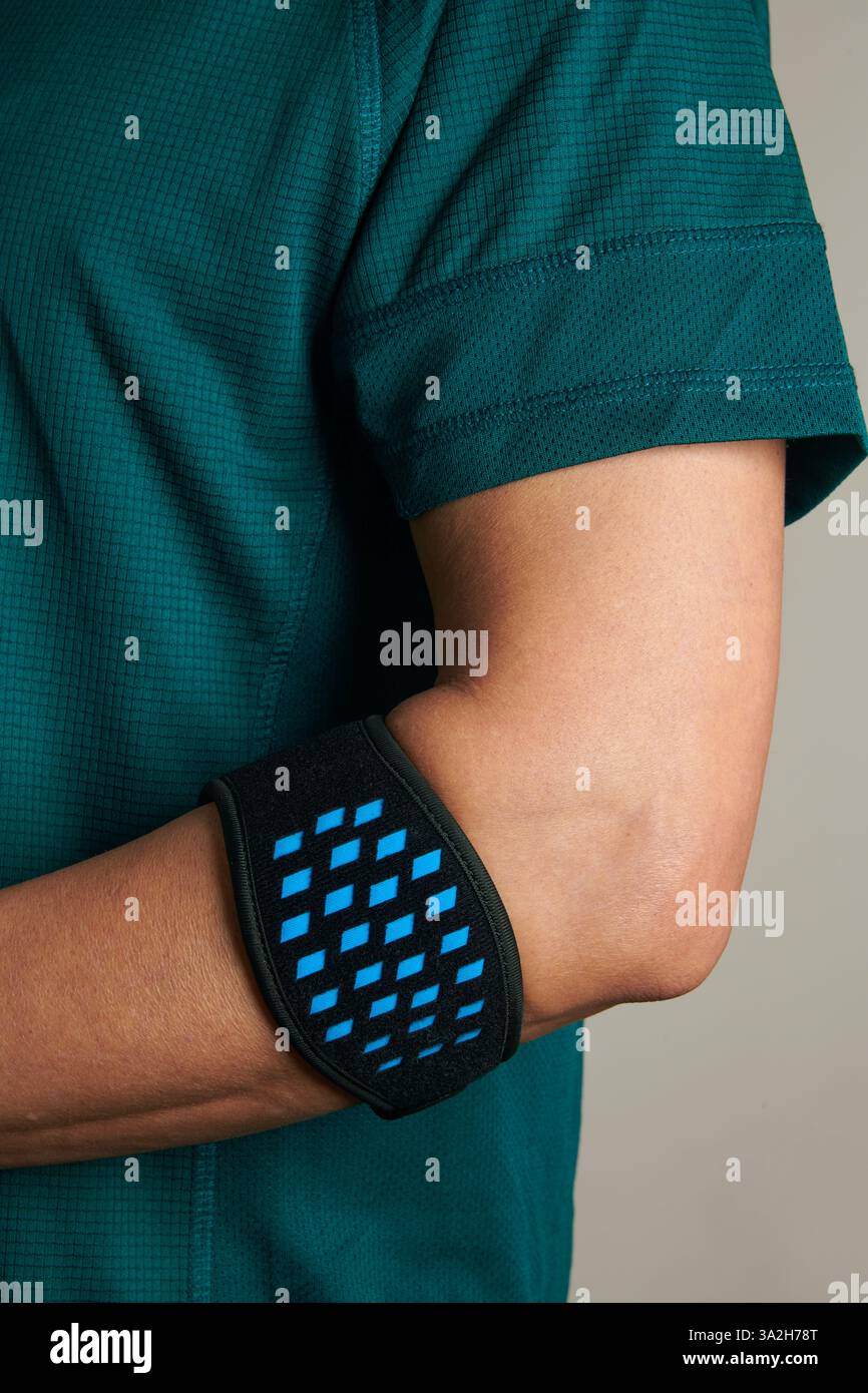gros plan d'un athlète portant un t-shirt de sport vert et un bracelet épicondylite sur son bras, pour soulager la douleur de l'épicondylite, également connue sous le nom de t Banque D'Images