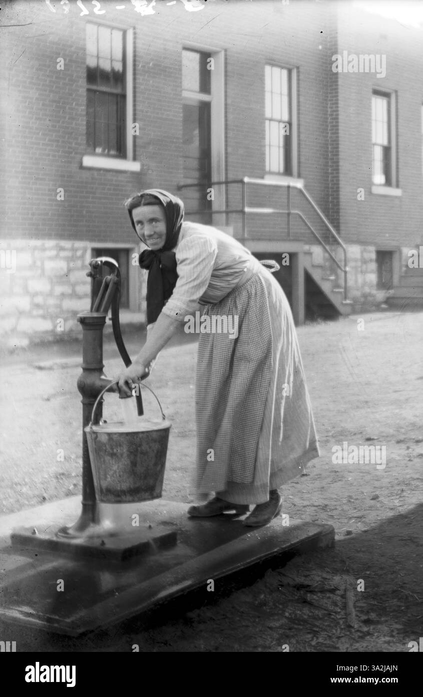 Femme non identifiée utilisant une pompe à eau dans un quartier Sud-Louis. Photographie de Richard Gruss, vers 1910. Musée d'histoire du Missouri photographies et collections de tirages. Gruss, Richard Collection. n28996. Banque D'Images