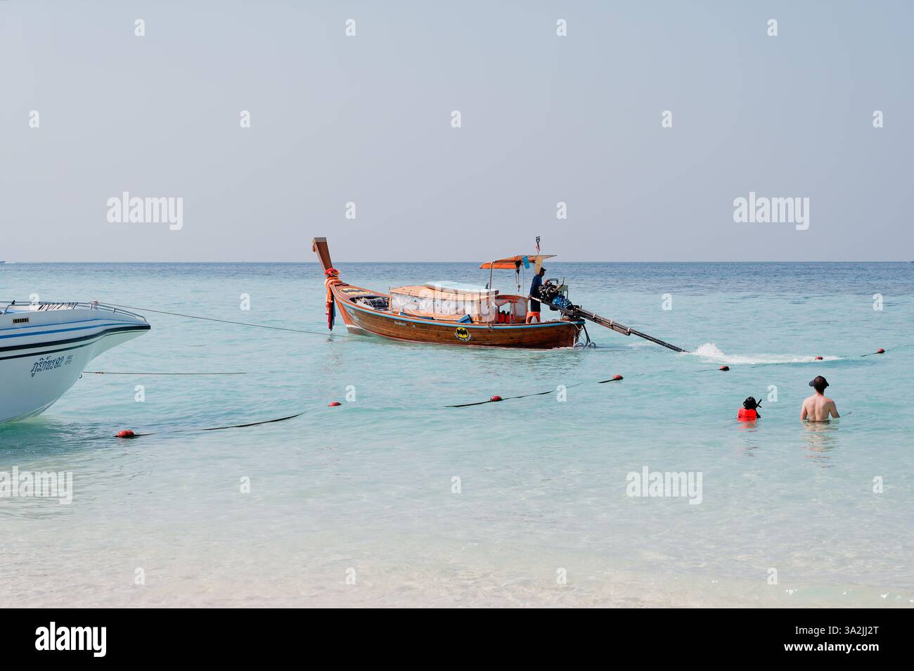 Un bateau à longue queue traditionnel flotte dans des eaux cristallines près d'une île tropicale lors d'une excursion en bateau au départ de Railay Banque D'Images