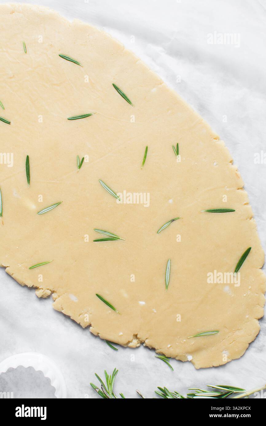 Vue de dessus de la pâte à biscuits au sucre romarin roulée, processus de fabrication des biscuits au sucre découpé Banque D'Images