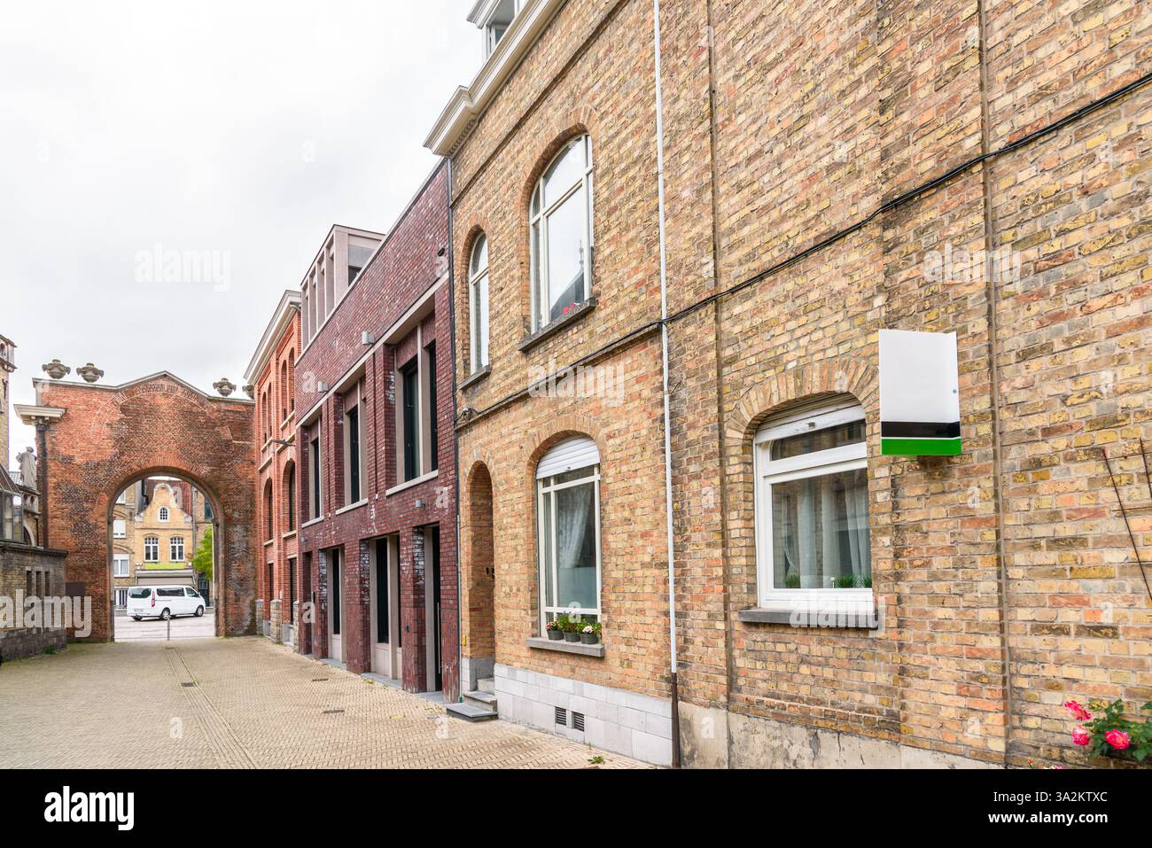 Signe immobilier vierge à l'extérieur d'une vieille maison de ville en briques le long d'une rue piétonne dans un centre-ville historique sur une journée nuageuse d'été Banque D'Images