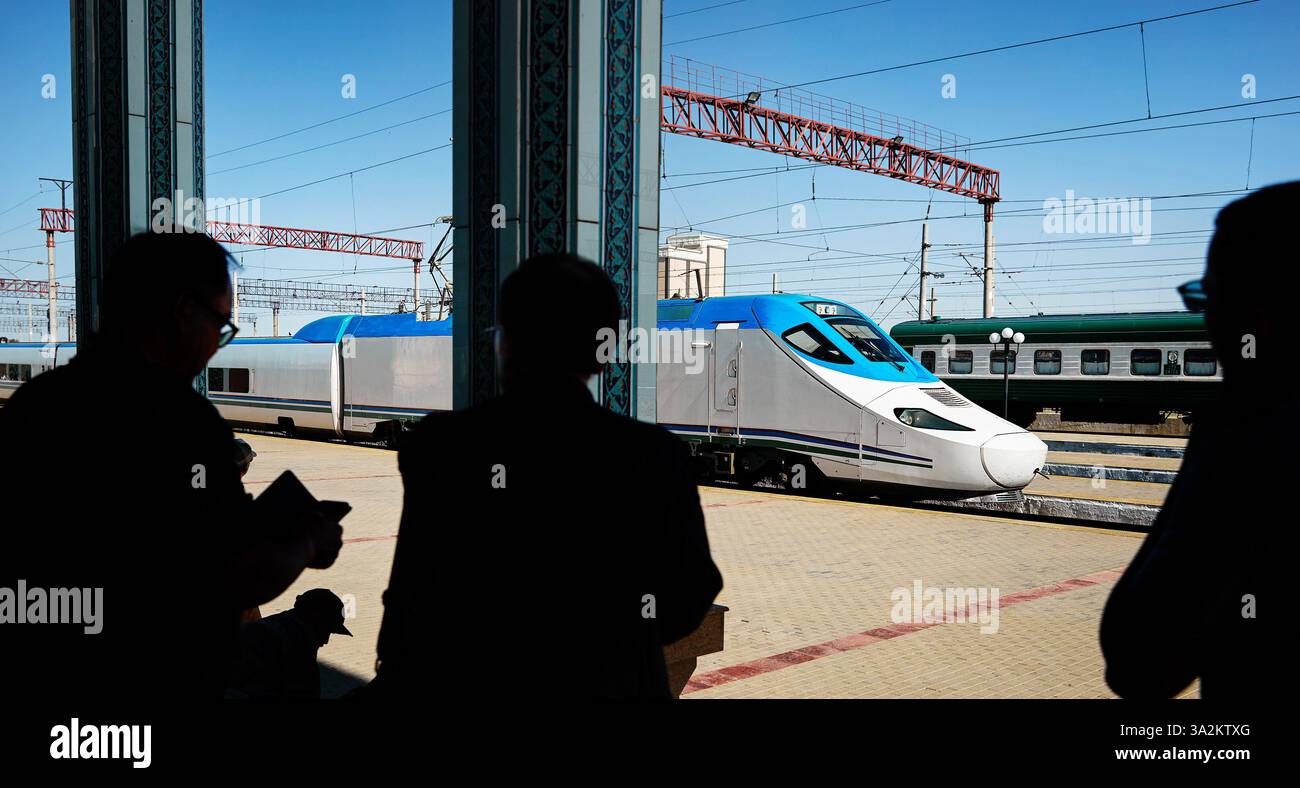 Afrosiyab train à grande vitesse de l'Ouzbékistan debout à la plate-forme à Boukhara Vokzal station et passager en silhouette en Ouzbékistan Banque D'Images