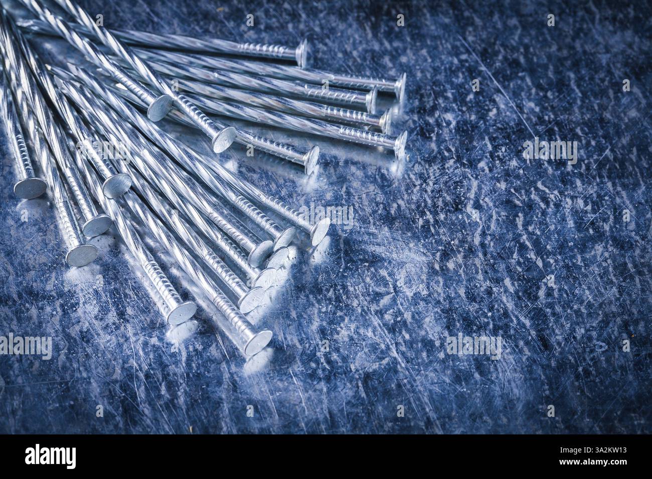 Clous de construction en acier inoxydable sur fond métallique rayé vue rapprochée concept de bâtiment Banque D'Images