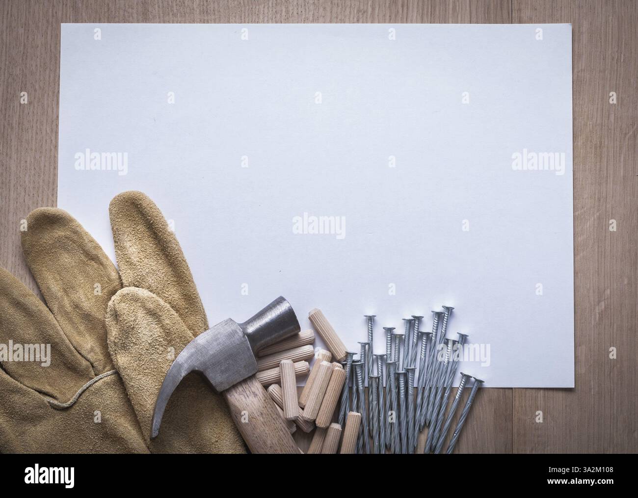 Feuille de papier clous en acier griffe marteau goupilles en bois et gants de protection en cuir sur le concept de construction copyspace de panneau de bois Banque D'Images