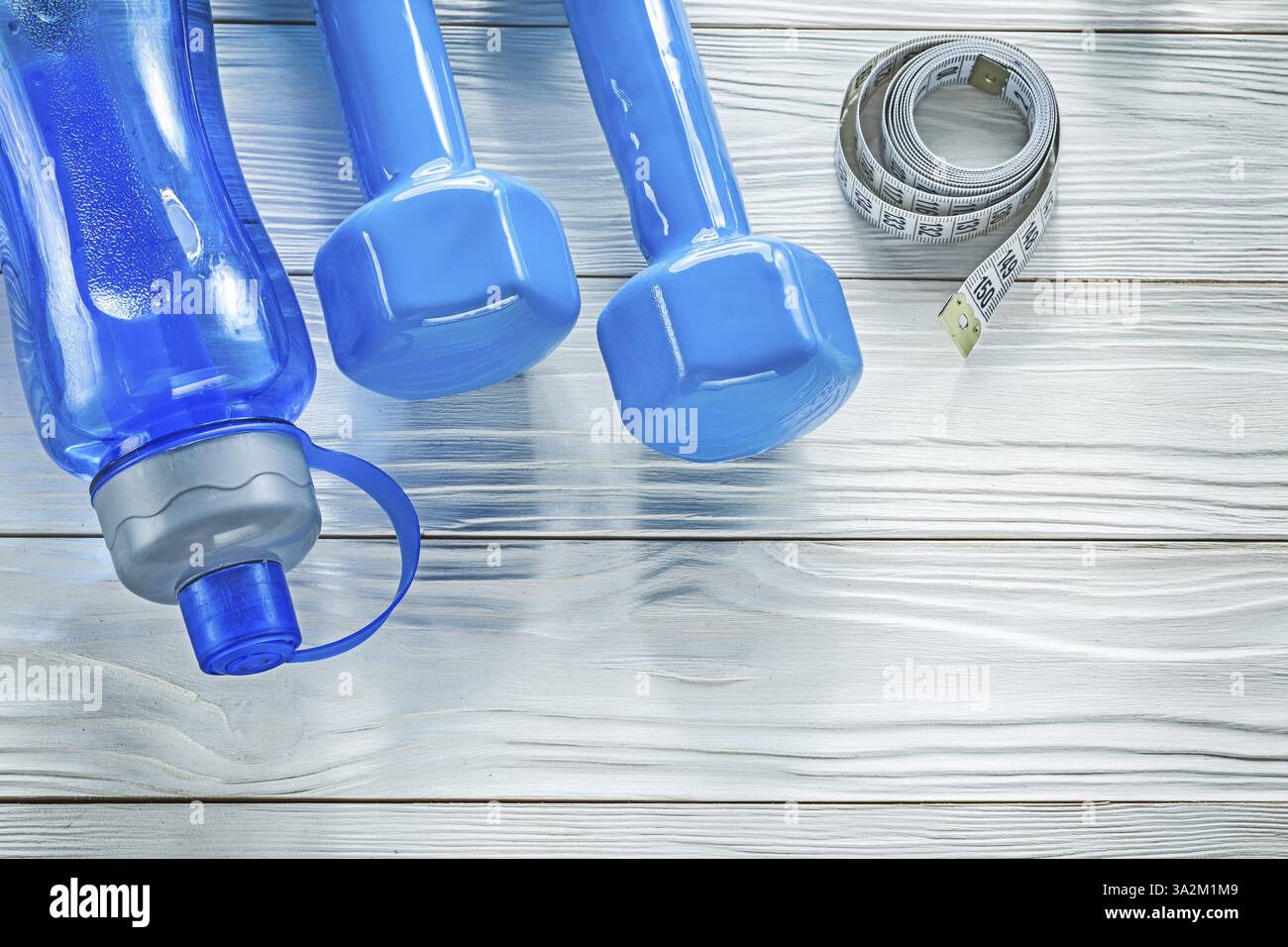 Ensemble de ruban à mesurer bouteille d'eau bleu haltères sur concept de fitness de planche en bois Banque D'Images