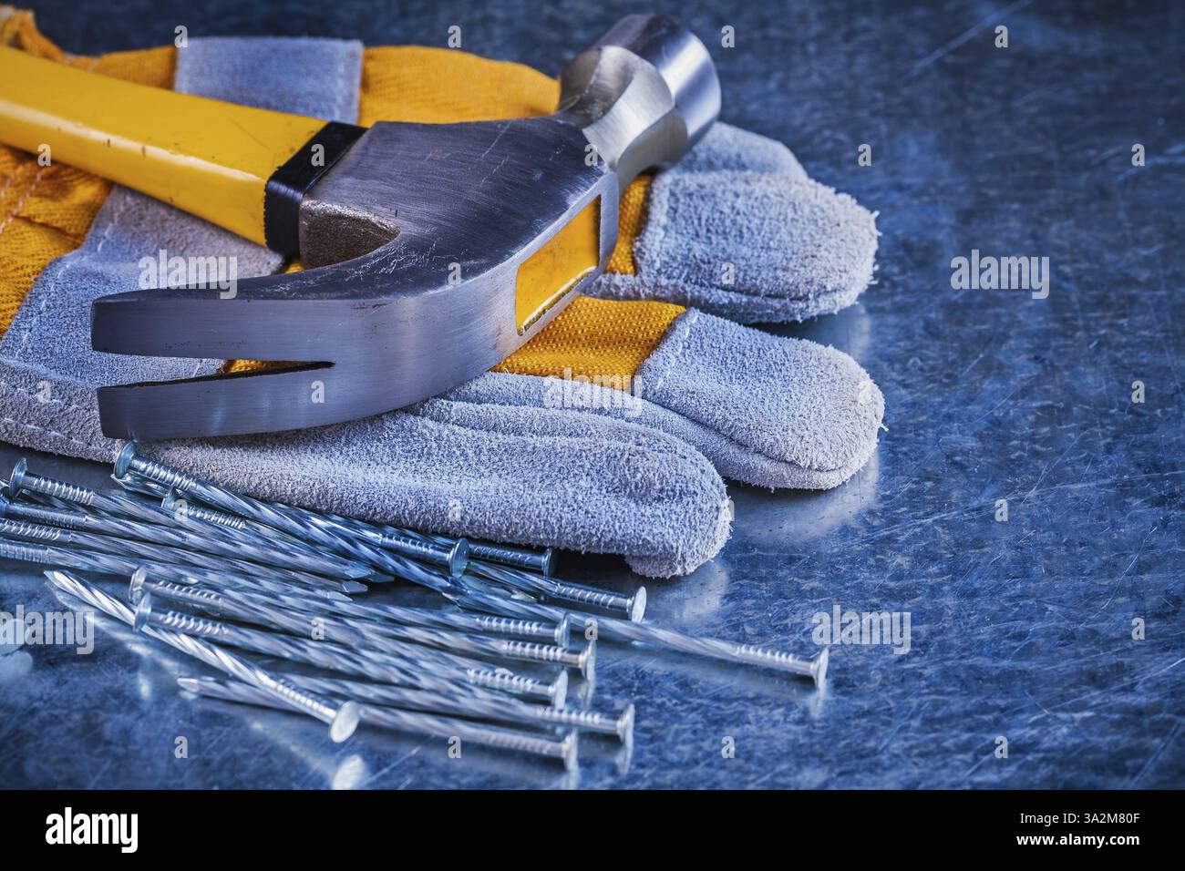 Tas de gants de sécurité de clous de construction et marteau à griffes sur le concept d'entretien de surface métallique rayée Banque D'Images