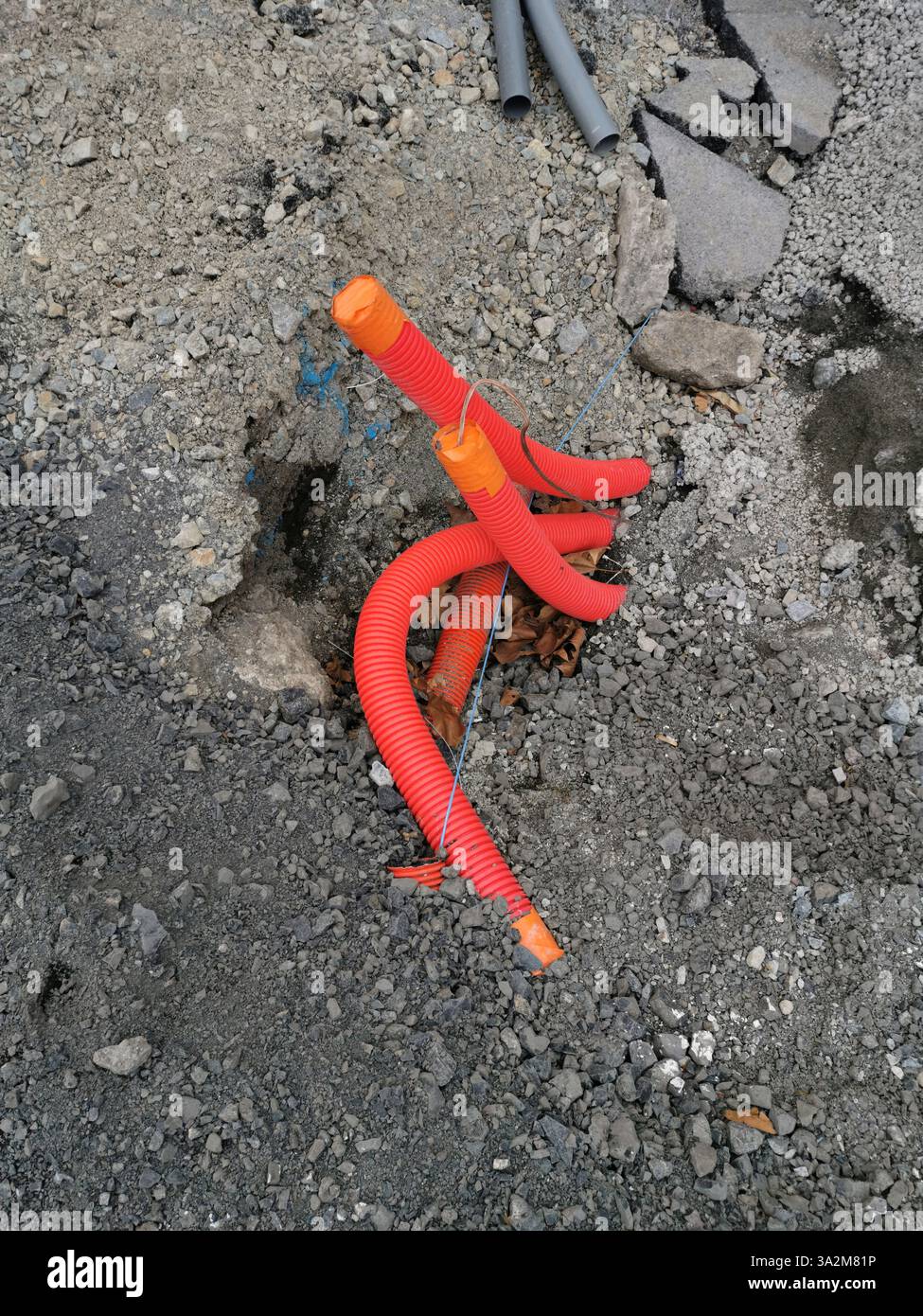 Des tuyaux orange vif émergent d'un chantier de construction avec du gravier et de la saleté par une journée ensoleillée Banque D'Images