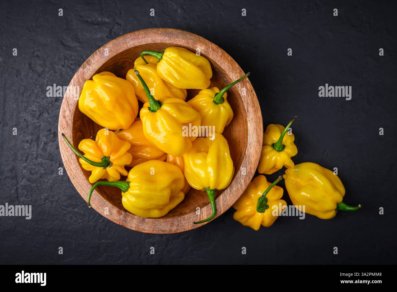 Vue de dessus de poivrons habanero jaunes mûrs (capsicum chinense) dans une assiette en bois de gros plan. Poivrons mexicains très chauds Banque D'Images