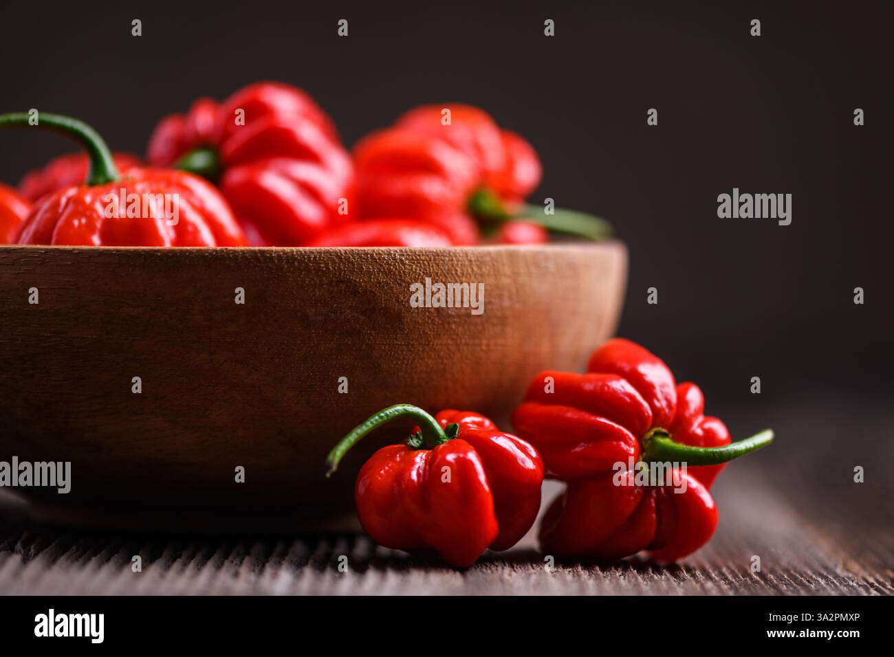 Poivrons rouges habanero mûrs (capsicum chinense) dans un bol en bois sur une table rustique. Les poivrons mexicains très chauds se rapprochent Banque D'Images