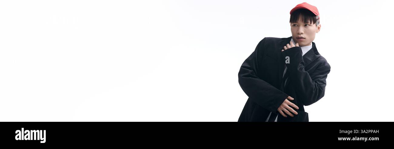 Confiant jeune homme asiatique vêtu d'une tenue tendance frappe une pose unique avec un look ludique. Banque D'Images