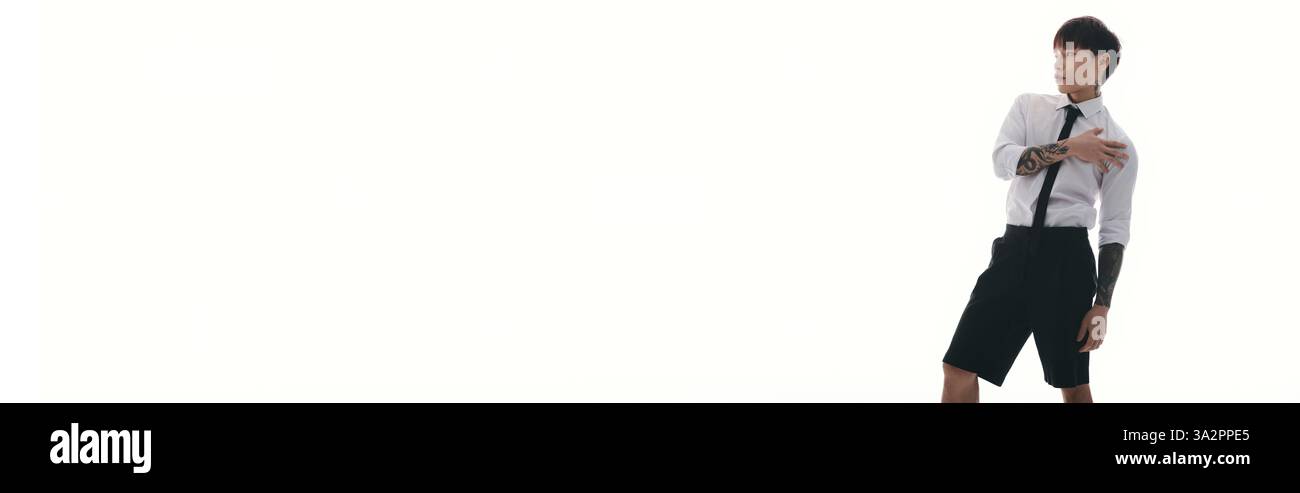 Jeune homme asiatique élégant pose en toute confiance dans une tenue sur mesure sur un fond simple. Banque D'Images