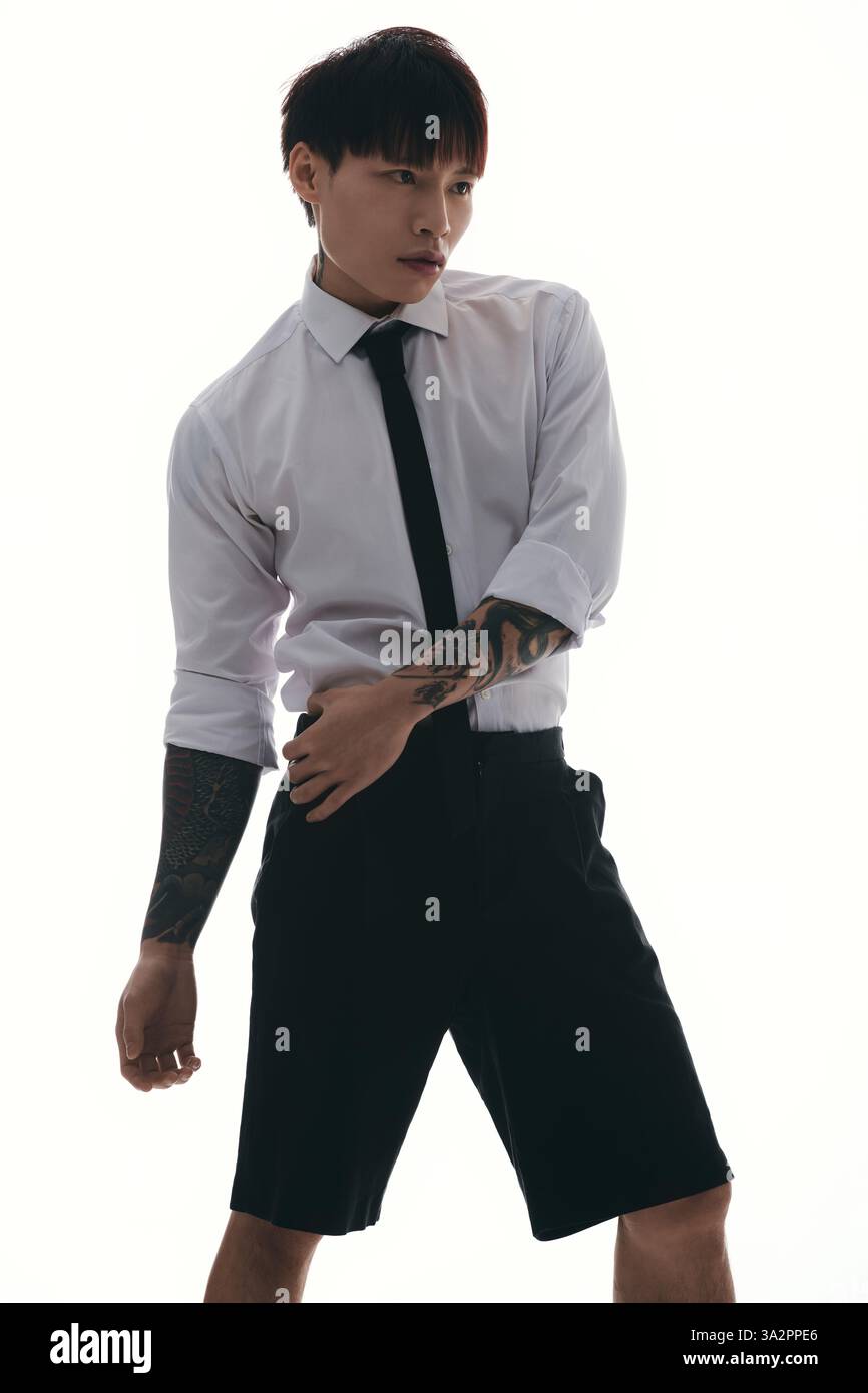 Un jeune homme asiatique magnifique prend une pose confiante, mettant en valeur son style unique et son tatouage réduit Banque D'Images