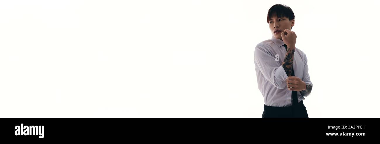 Un jeune homme asiatique attrayant ajuste sa cravate tout en mettant en valeur sa tenue élégante et son charme. Banque D'Images