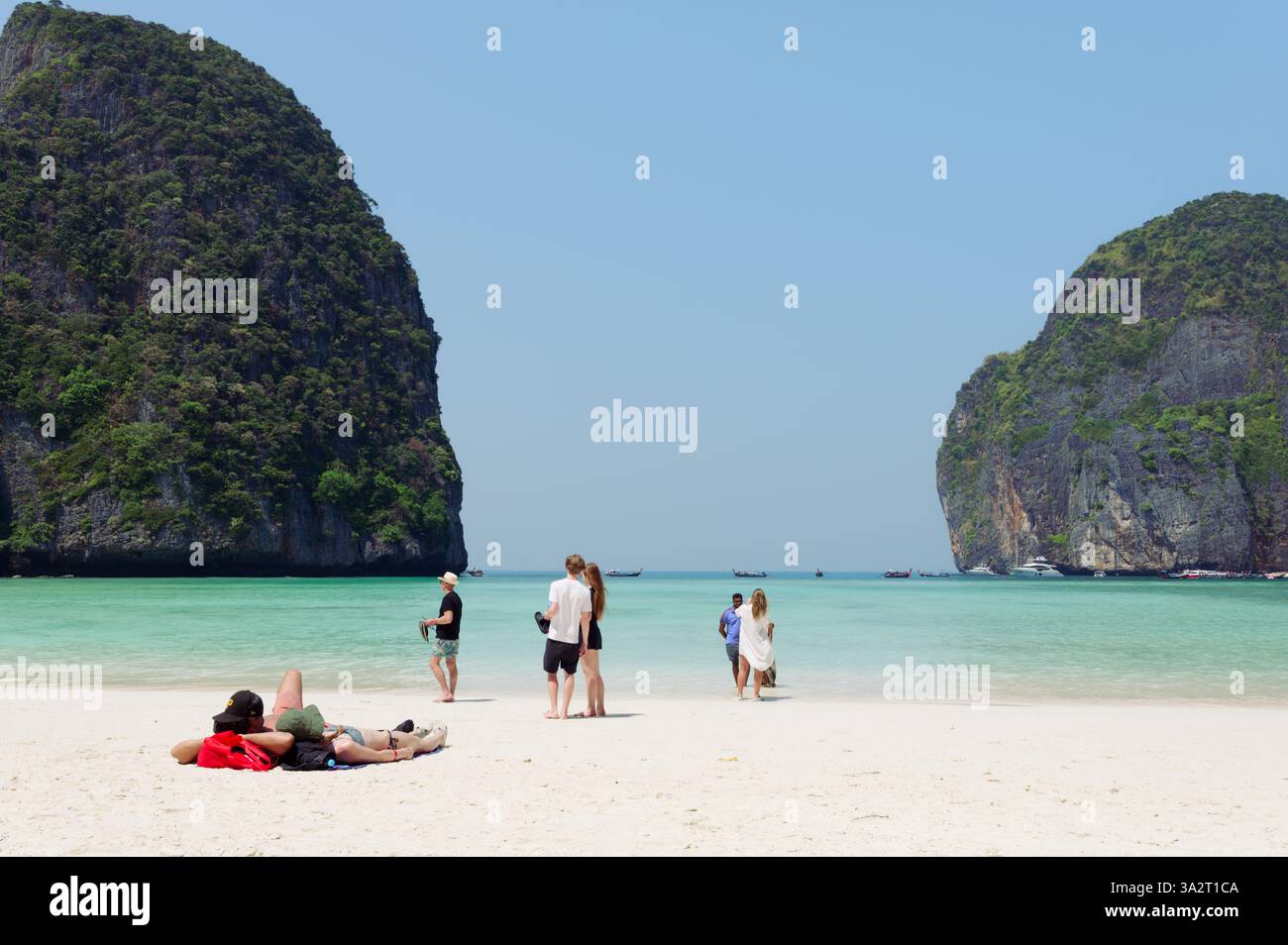 Les touristes se détendent sur du sable blanc doux, entouré de falaises imposantes et d'eaux turquoises Banque D'Images