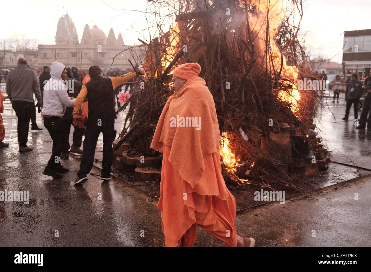 Londres, Royaume-Uni. 13 mars 2025. Les dévots assistent à une cérémonie rituelle où les pandits allument un feu de joie en face des terrains du temple de Neasden BAPS Swaminarayan, suivie par des offrandes de noix de coco et des festivités colorées. ©Simon King/ Alamy Live News Banque D'Images