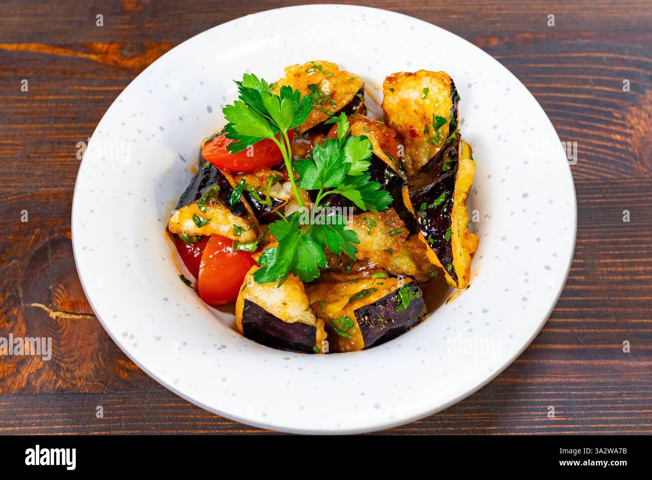 Un plat vibrant composé d'aubergines sautées avec des tomates colorées et des herbes fraîches. La présentation souligne la fraîcheur, ce qui en fait un OPT invitant Banque D'Images