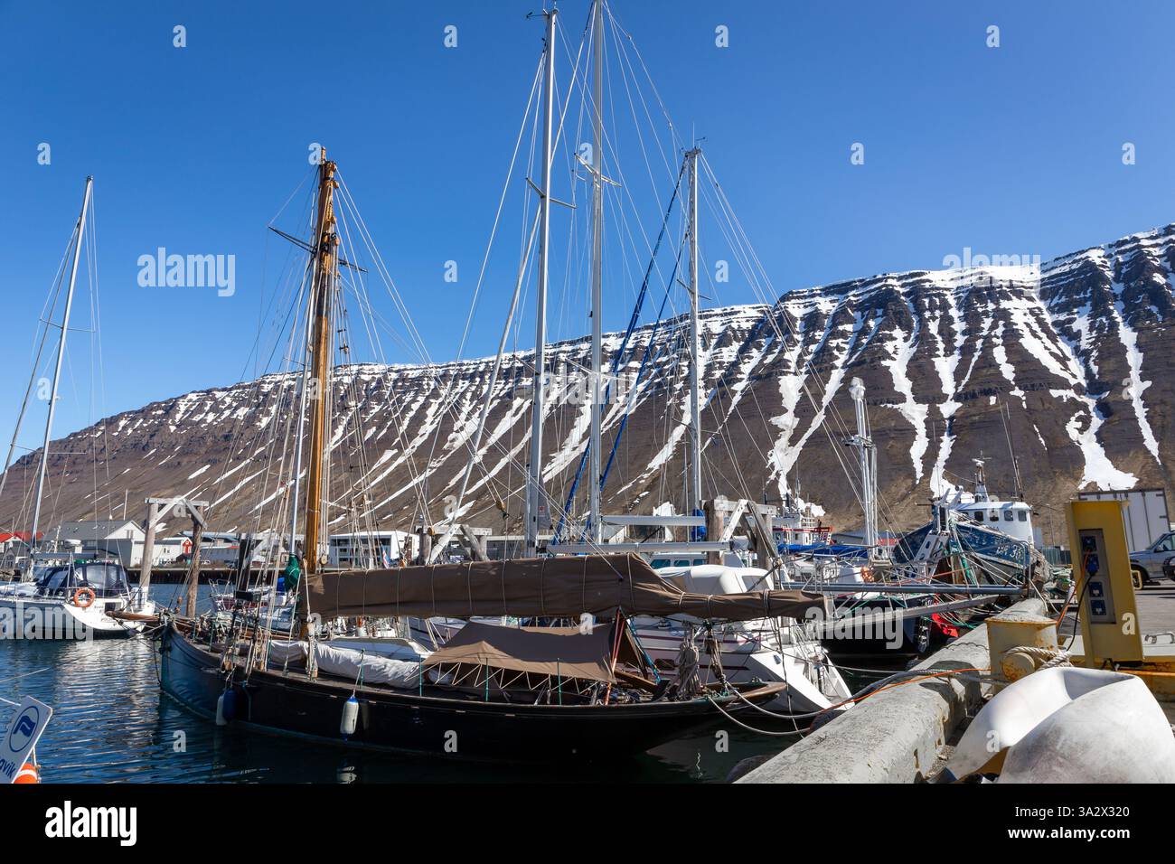 Isafjordur, Islande, 23.05.22. Port d'Isafjordur avec des yachts et des navires amarrés et des montagnes volcaniques enneigées en arrière-plan. Banque D'Images