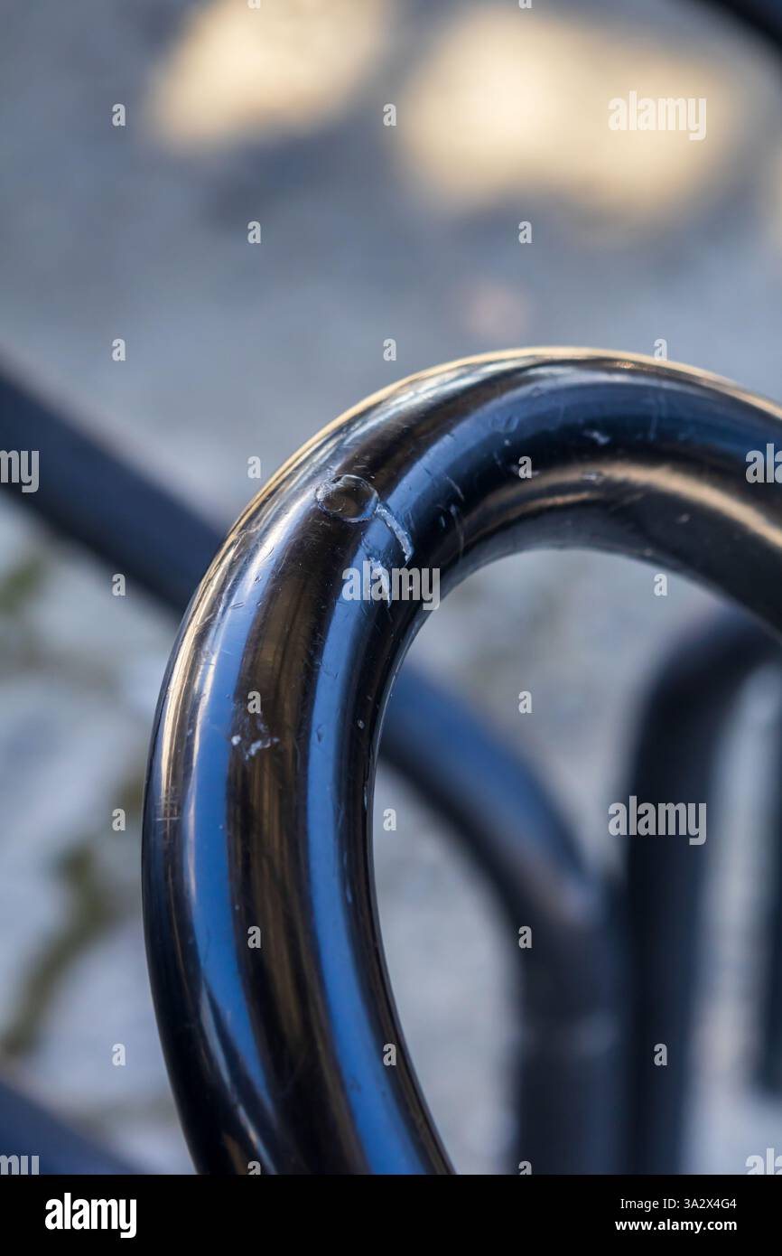 Gros plan d'une barre métallique tubulaire peinte en noir, pliée en demi-cercle, créant une forme abstraite Banque D'Images