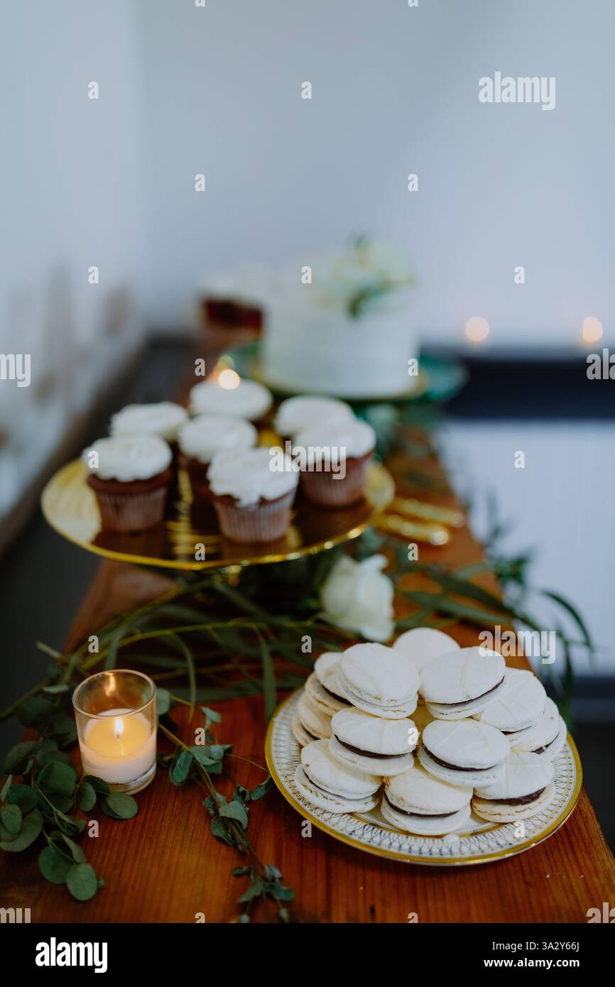 Élégante table à desserts décorée de macarons, de cupcakes et de chandelles Banque D'Images
