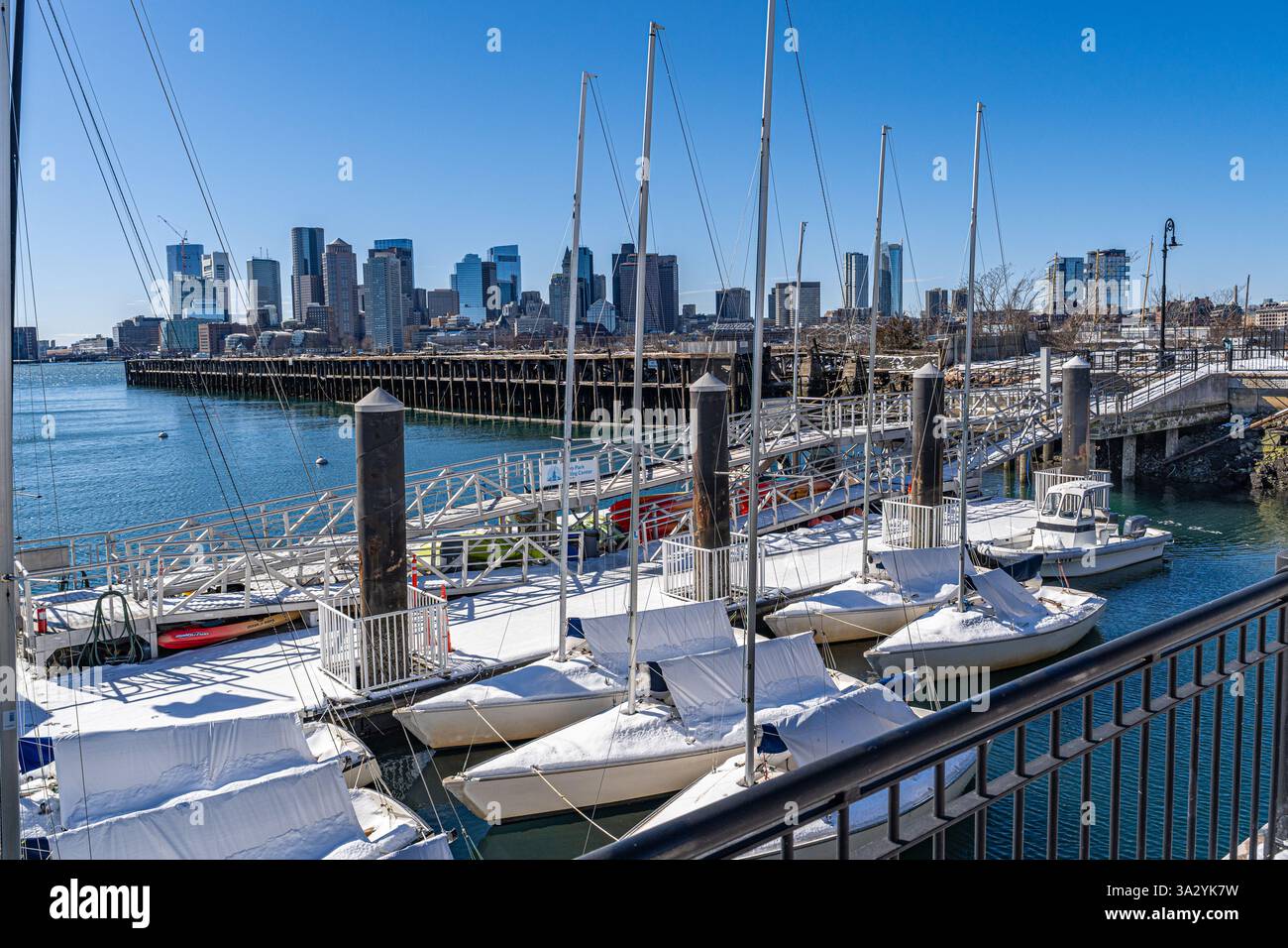 Boston, ma, États-Unis - 21 février 2025 - stationné de petits voiliers couverts de neige d'hiver à Piers Park à East Boston avec une ligne d'horizon lointaine de Boston dans le dos Banque D'Images