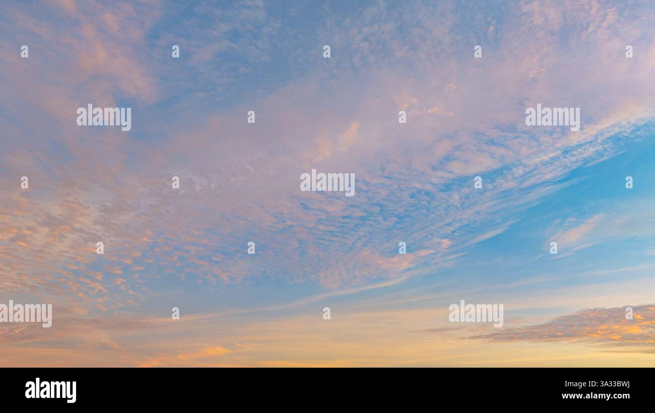 Vue aérienne Une vue imprenable sur une ville côtière au coucher du soleil, avec des teintes dorées illuminant le ciel et se reflétant sur l’océan calme. Petites îles et Banque D'Images