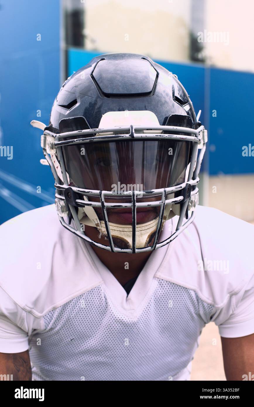 Un joueur de football américain vêtu d'un uniforme complet et d'un casque, prêt à l'action. La scène capture l'intensité et l'esprit du sport, en mettant l'accent sur o Banque D'Images
