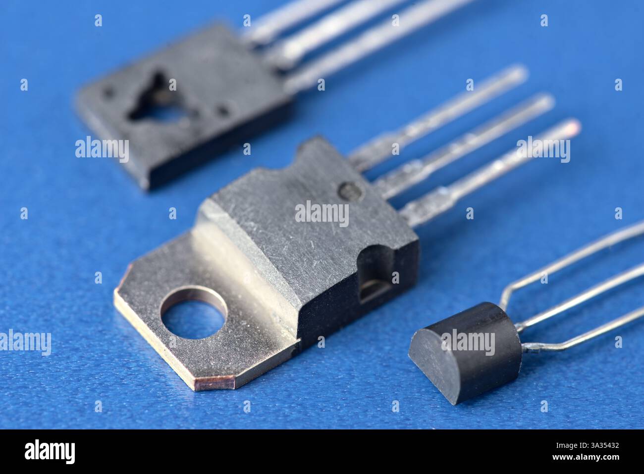 Une image détaillée montrant un assortiment de composants électroniques, y compris des transistors et des condensateurs, sur fond bleu. Banque D'Images