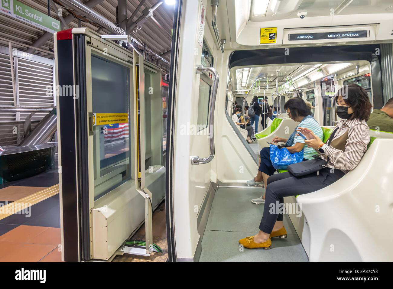 Portes, porte ouverte, plate-forme, l'intérieur d'un train RapidKL Scomi SUTRA à Kuala Lumpur, Malaisie, les femmes navettrices à bord assis Banque D'Images