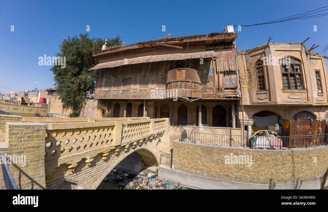 Bâtiment historique en brique avec balcon en bois et pont voûté sur une petite rivière. En Irak, Bassorah Banque D'Images