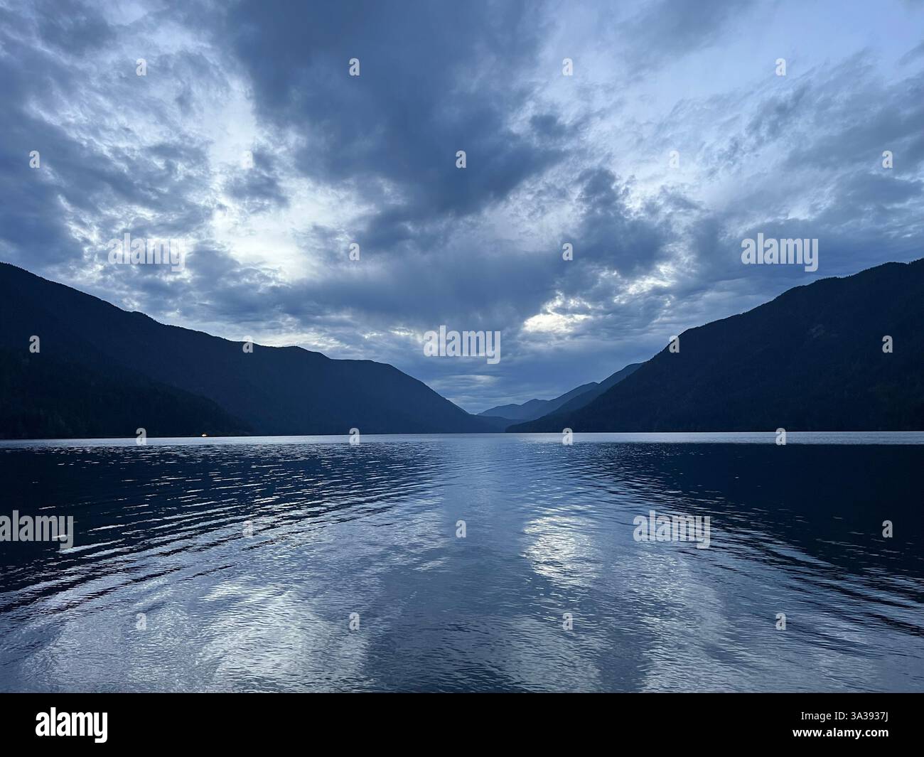 Soirée crépuscule Lake Crescent entre les montagnes ombres sur l'eau nuages dramatiques dans le ciel sombre montagnes bleu gris couleurs lac Crescent olympique Banque D'Images