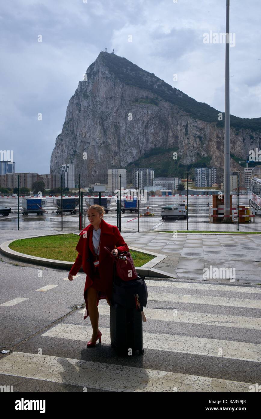 Hôtesse de l'air British Airways près de la piste de l'aéroport de Gibraltar, avec le rocher emblématique de Gibraltar en arrière-plan sous un ciel orageux. Banque D'Images