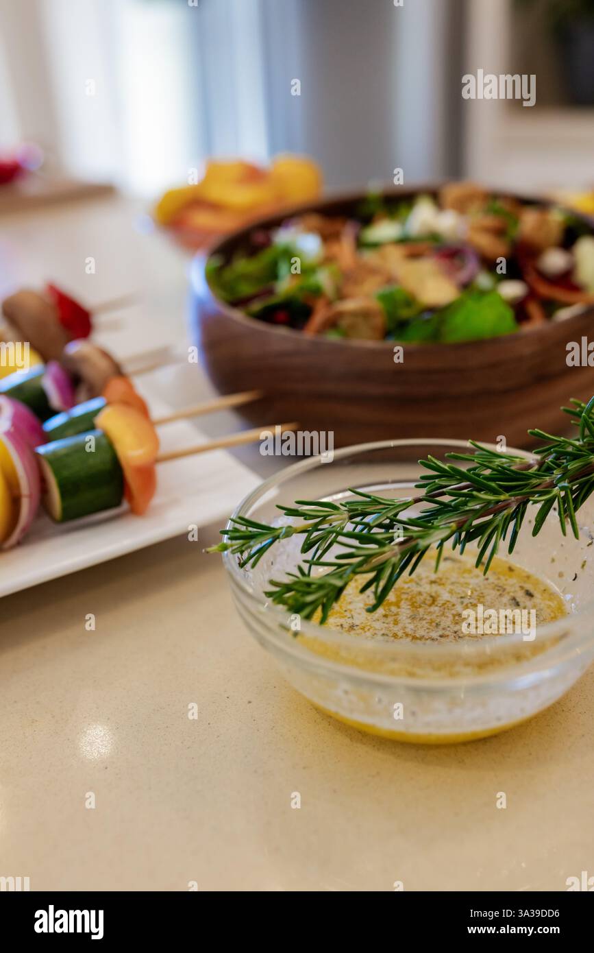 Salade fraîche et brochettes de légumes avec vinaigrette au romarin sur le comptoir de la cuisine Banque D'Images