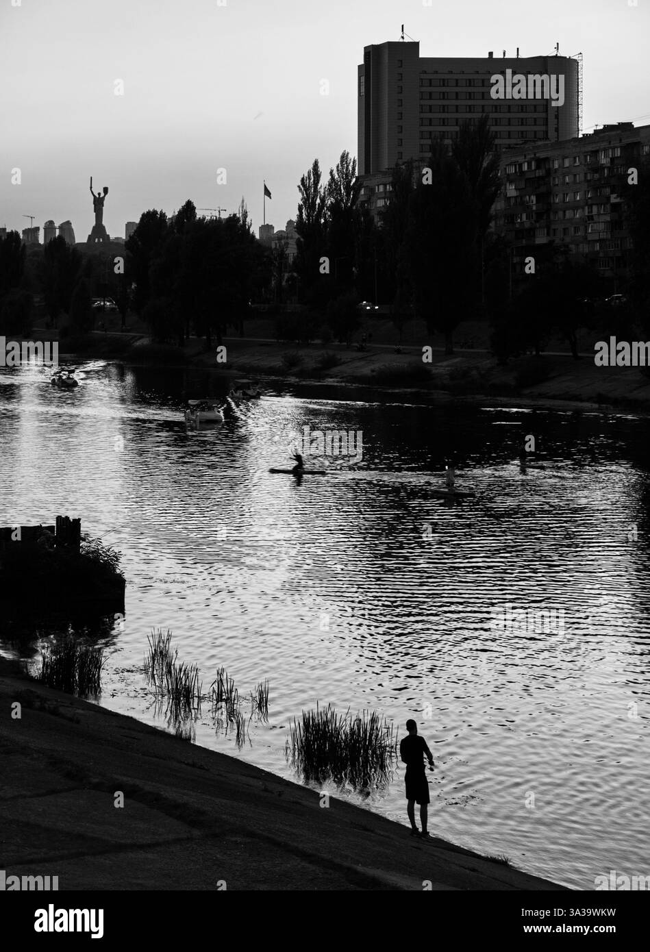 Pêcheur debout à la rive de la rivière Dnipro contre mère Ukraine monument, qui s'élève au-dessus du canal de la rivière Dnipro Banque D'Images