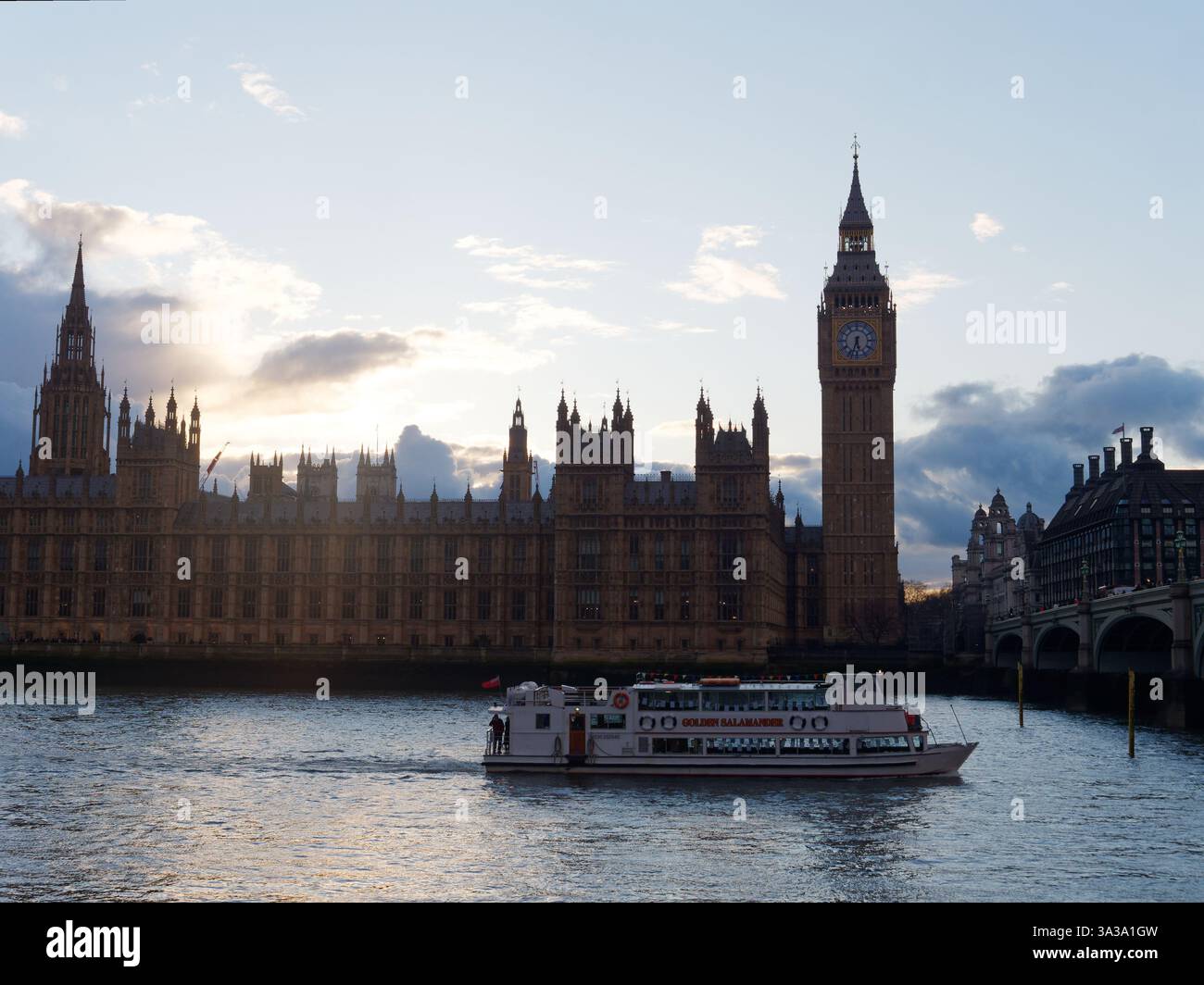 Un bateau navigue le long de la Tamise tandis que l'emblématique tour de l'horloge et le Parlement se dressent majestueusement contre un ciel nuageux. Londres, mars 2025 Banque D'Images