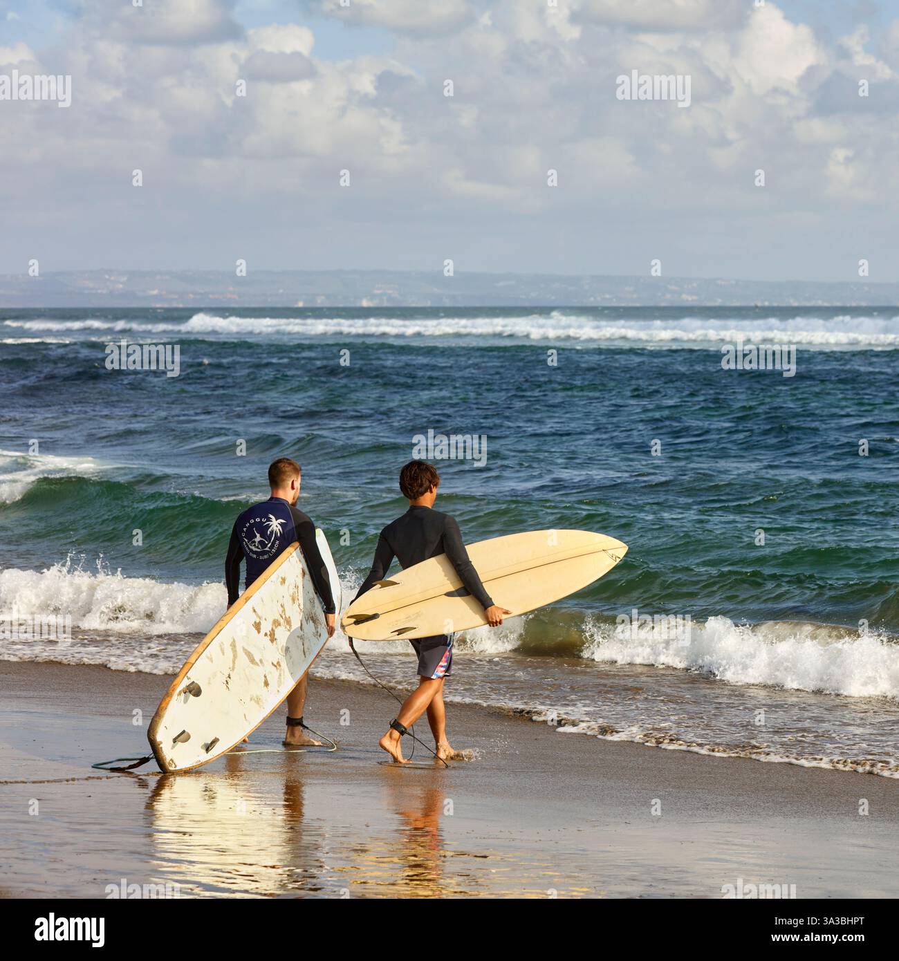 Moniteur de surf local et son élève marchent vers la mer pour une séance de formation portant leurs planches de surf. Plage de Canggu, Bali, Indonésie. Banque D'Images