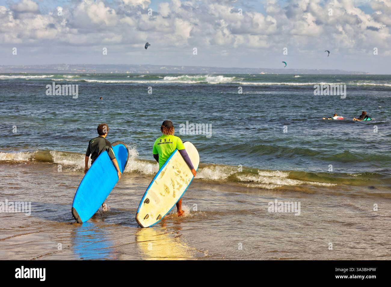 Moniteur de surf local et son élève marchent vers la mer pour une séance de formation portant leurs planches de surf. Plage de Canggu, Bali, Indonésie. Banque D'Images