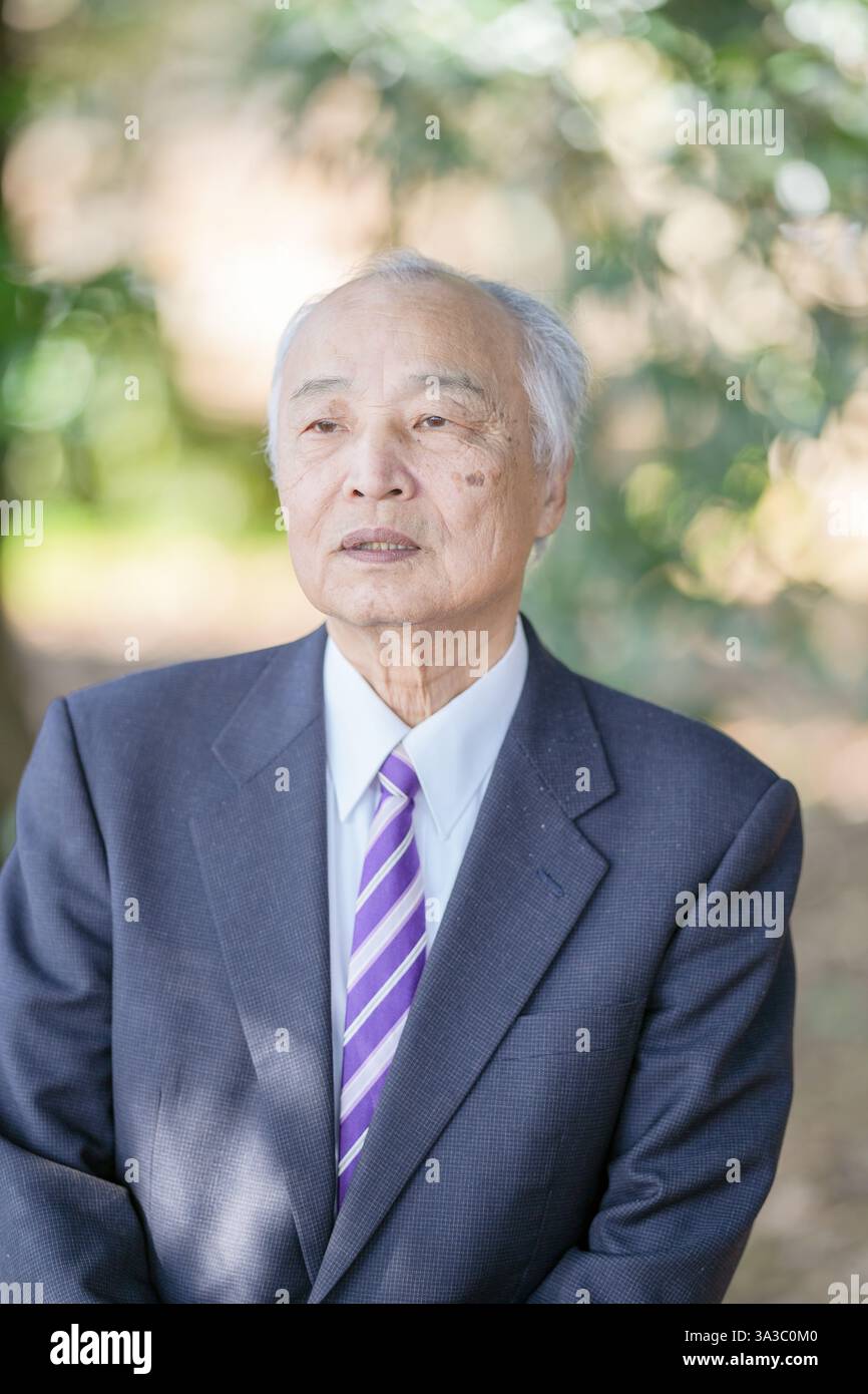 Un parc sur une agréable journée de printemps avec beaucoup de verdure au Japon. Un Japonais à la fin des années 70 portant un costume se lève. Banque D'Images