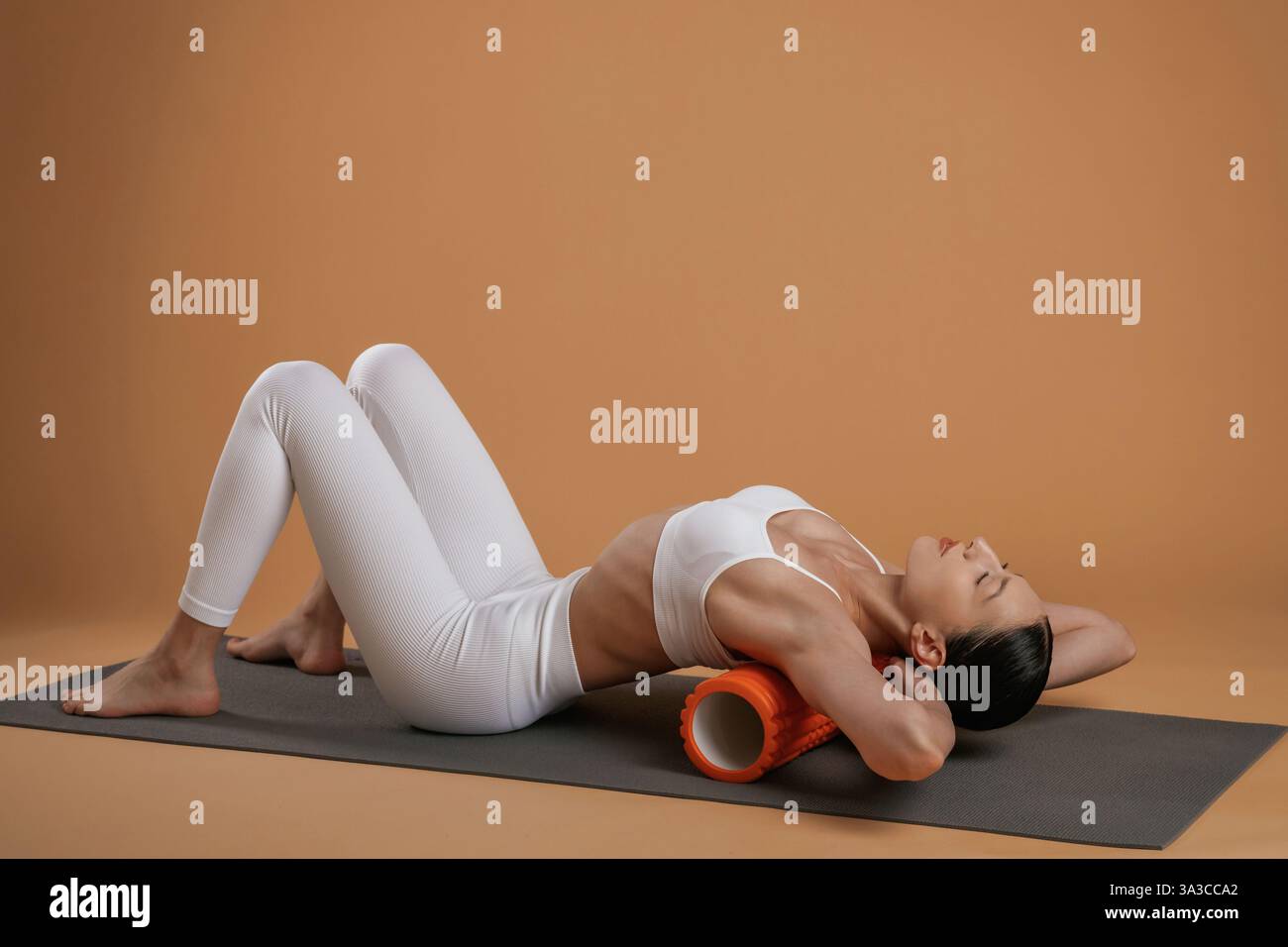 Utilisation du rouleau sur le tapis de yoga. Belle femme de fitness est dans le studio. Banque D'Images
