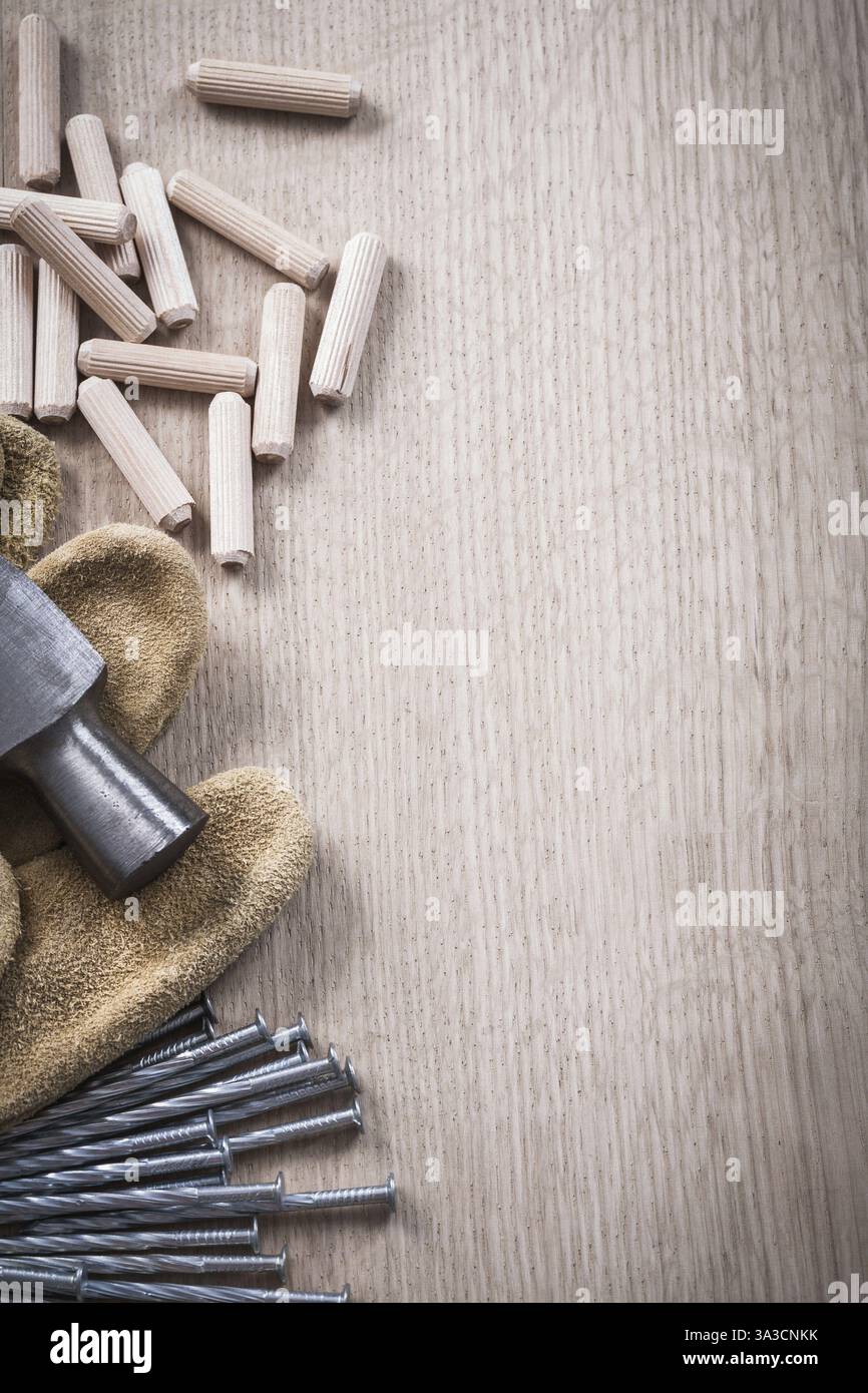 Pile de chevilles en bois griffes marteau gants de protection en cuir et clous en métal sur planche de bois close up view concept de construction Banque D'Images