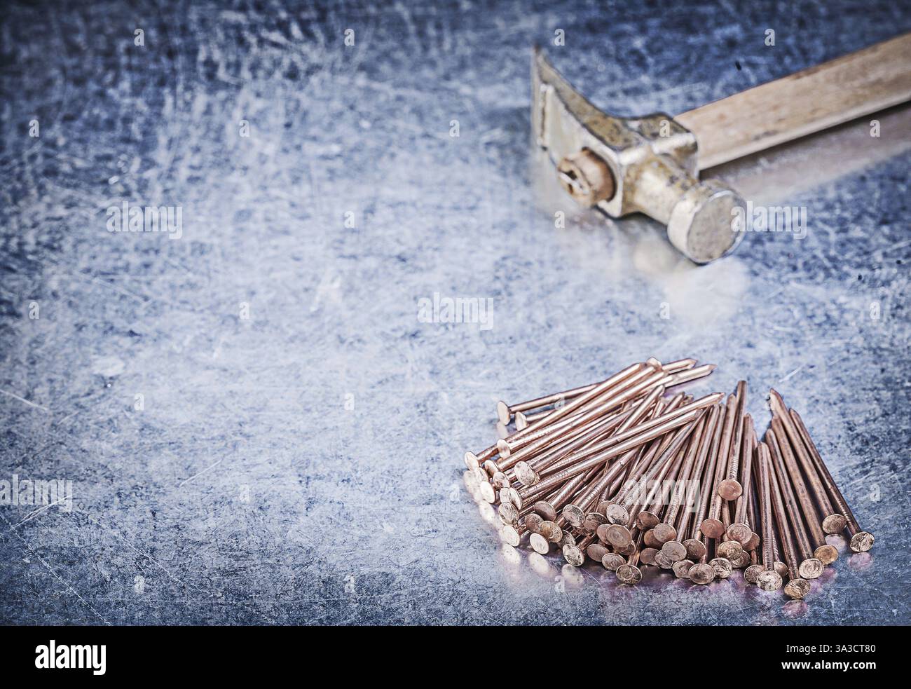 Pile de marteau à griffe vintage de clous de construction en cuivre sur fond métallique Banque D'Images