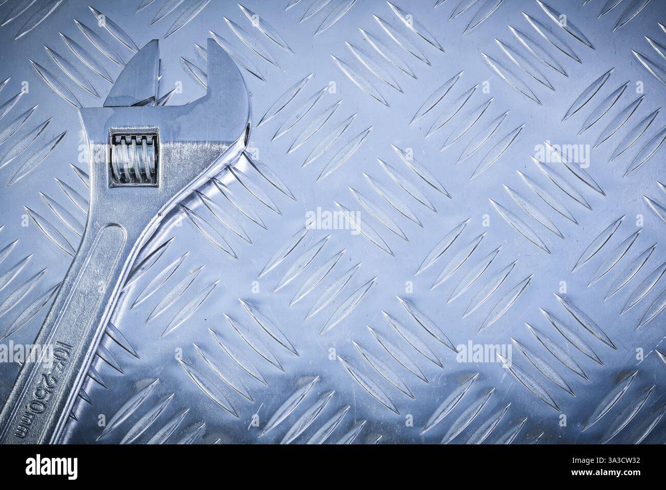 Clé réglable en acier inoxydable sur concept de construction de plaque métallique rainurée Banque D'Images