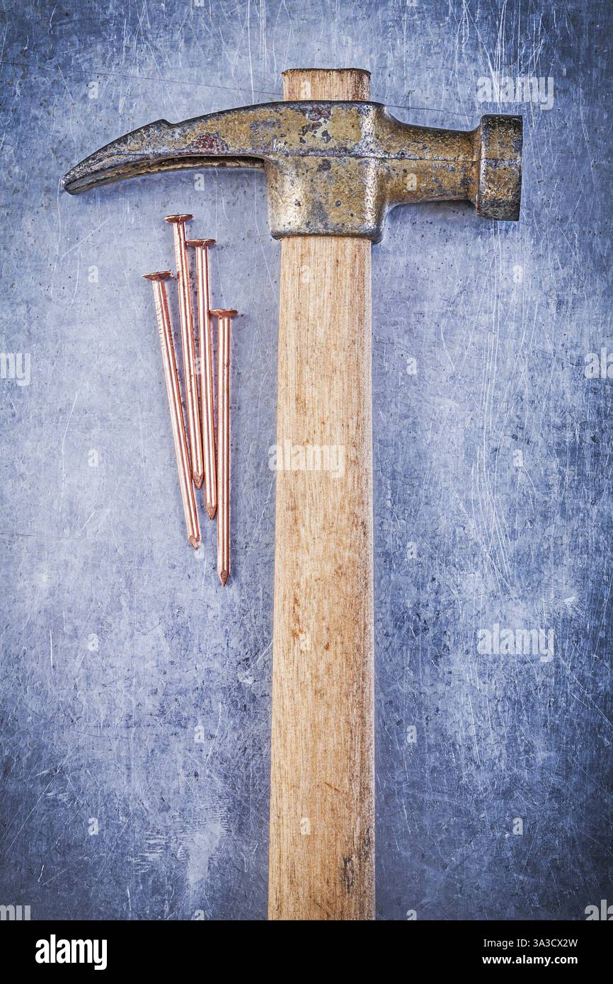 Clous de construction en cuivre de marteau à griffes vintage sur l'image verticale de fond métallique Banque D'Images