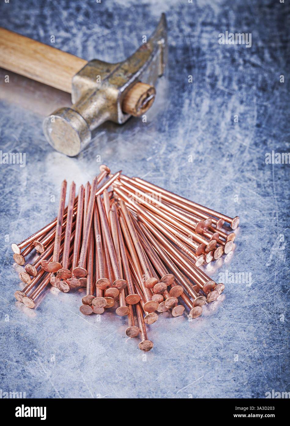 Tas de marteau à griffe vintage de clous de construction en cuivre sur fond métallique rayé Banque D'Images