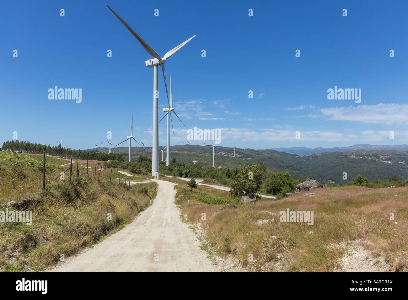 Plusieurs grands moulins à vent modernes sur les montagnes avec route déserte et ciel bleu dans la région de Fafe au Portugal Banque D'Images