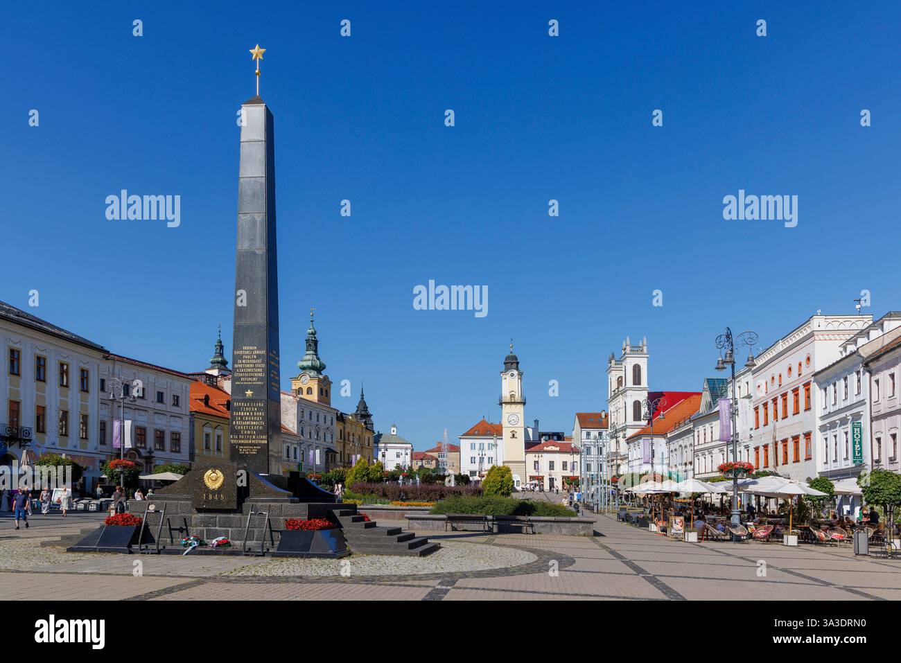 Mémorial de guerre sur la place principale avec des gens mangeant et buvant dans un restaurant en plein air, Banska Bystrica, Slovaquie Banque D'Images