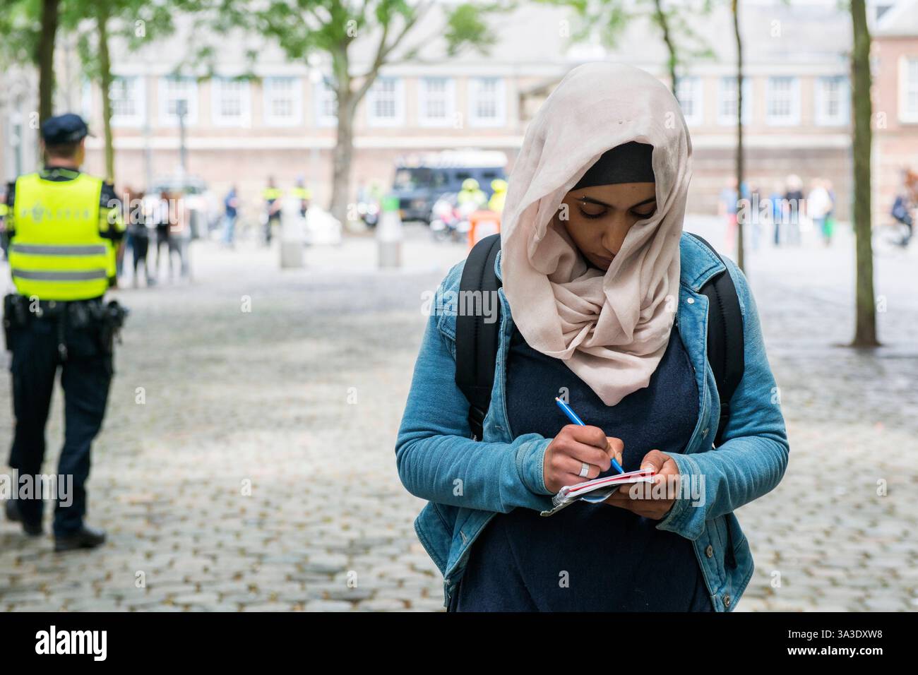 Jeune femme néerlando-égyptienne prenant des notes jeune femme néerlando-égyptienne prenant des notes, après avoir été confrontée à des partisans de Pegida. Breda, pays-Bas. Breda Binnenstad / Kasteelplein e.o. Noord-Brabant Nederland Copyright : xGuidoxKoppesxPhotox Banque D'Images