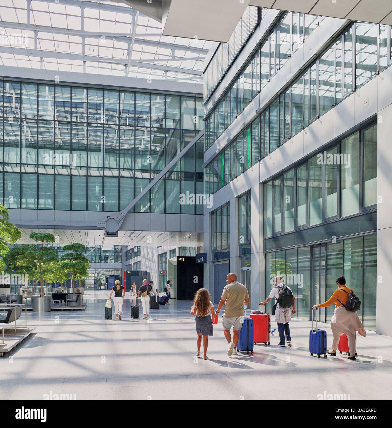 Diverses familles avec des bagages colorés sur le chemin de leurs trains et avions à l'énorme complexe de l'aéroport de Francfort appelé le Squaire. Banque D'Images