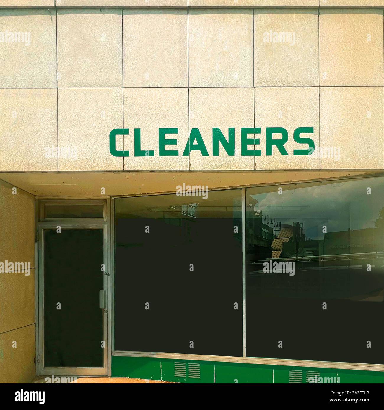La devanture du magasin de nettoyage à sec présente une façade carrelée, un lettrage vert audacieux et une entrée en verre élégante, reflétant l'architecture commerciale du milieu du siècle. Banque D'Images