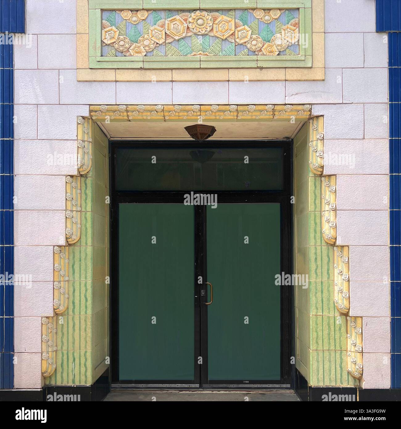 Porte vintage ornée encadrée par des carreaux décoratifs Art Déco dans les tons de vert, bleu et jaune, à Chicago. - Image de stock capturée avec un smartphone